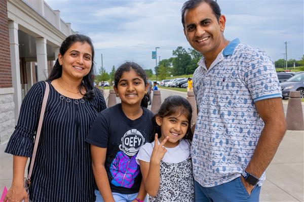 family smiling outside of school